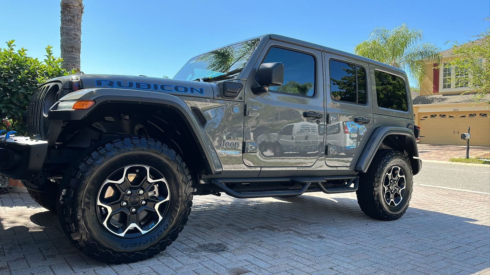 A jeep wrangler is parked in a driveway in front of a house.
