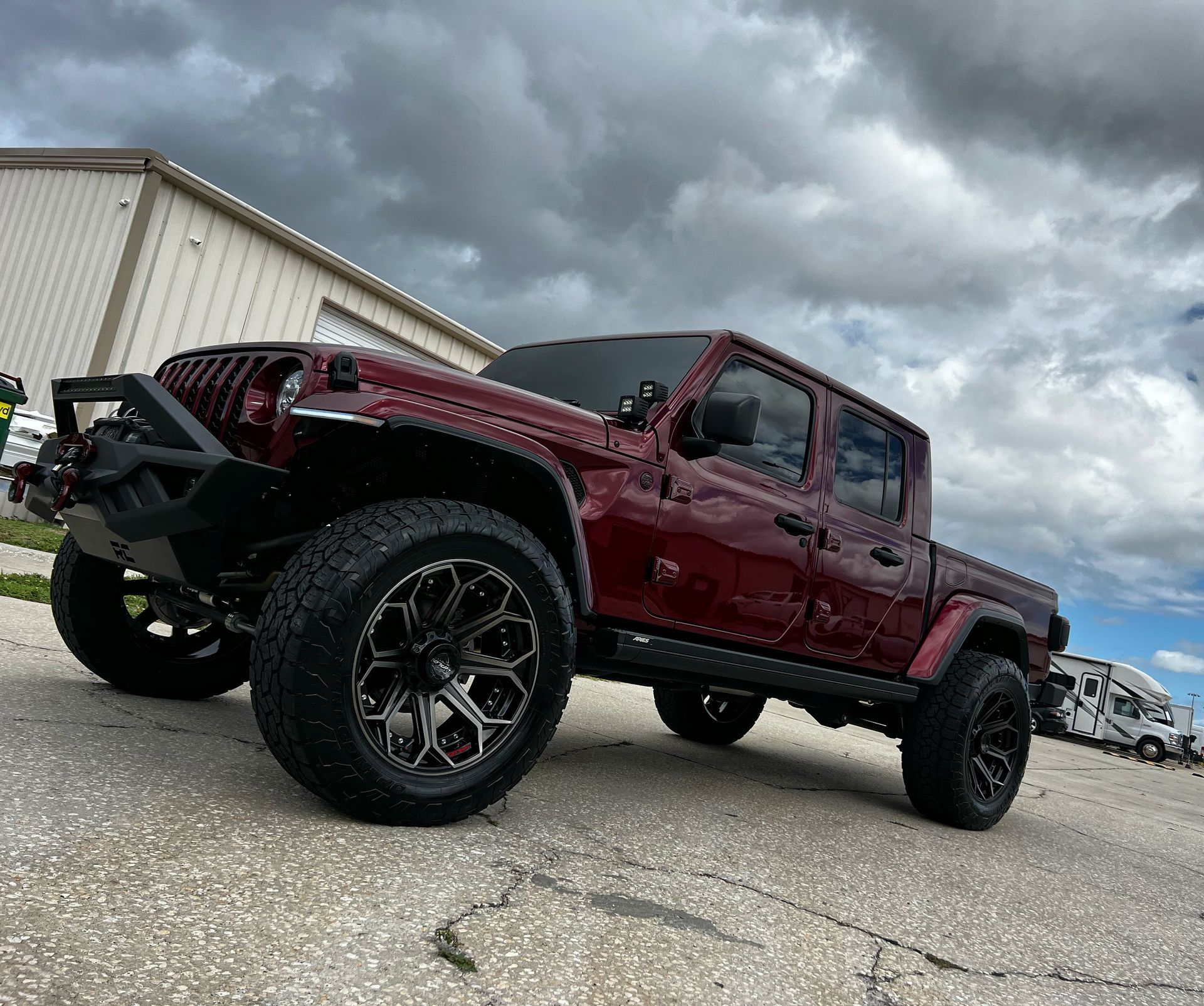 A red jeep is parked on the side of the road in front of a building.