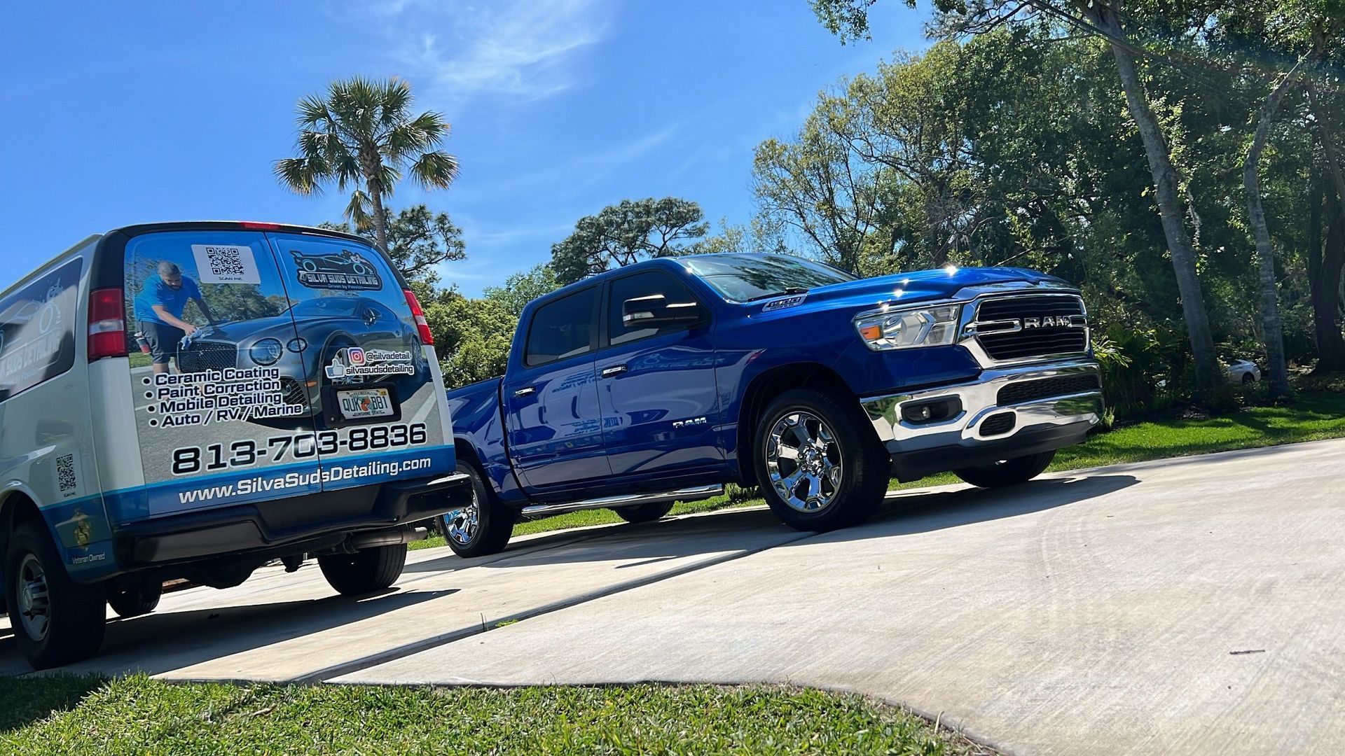 A blue truck and a white van are parked on the side of the road.