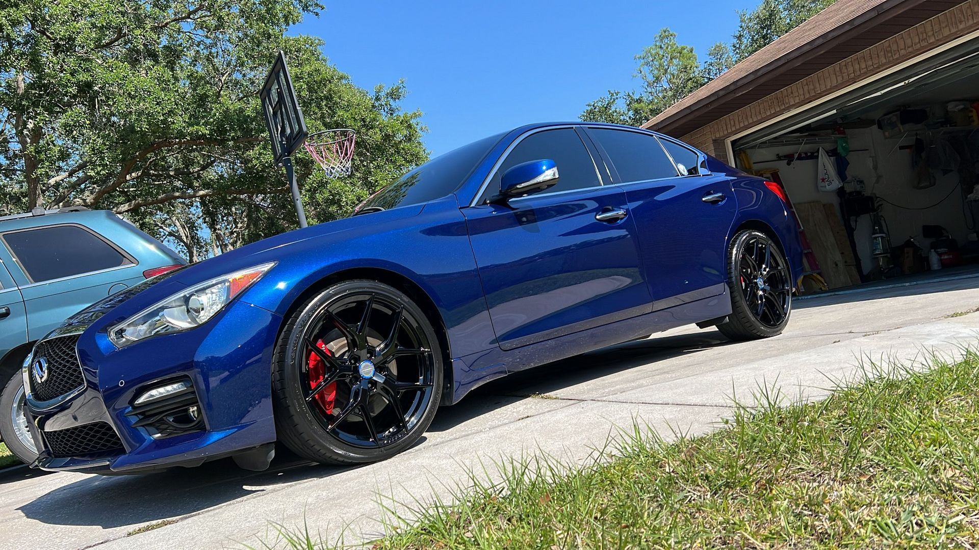A blue car is parked in front of a garage.