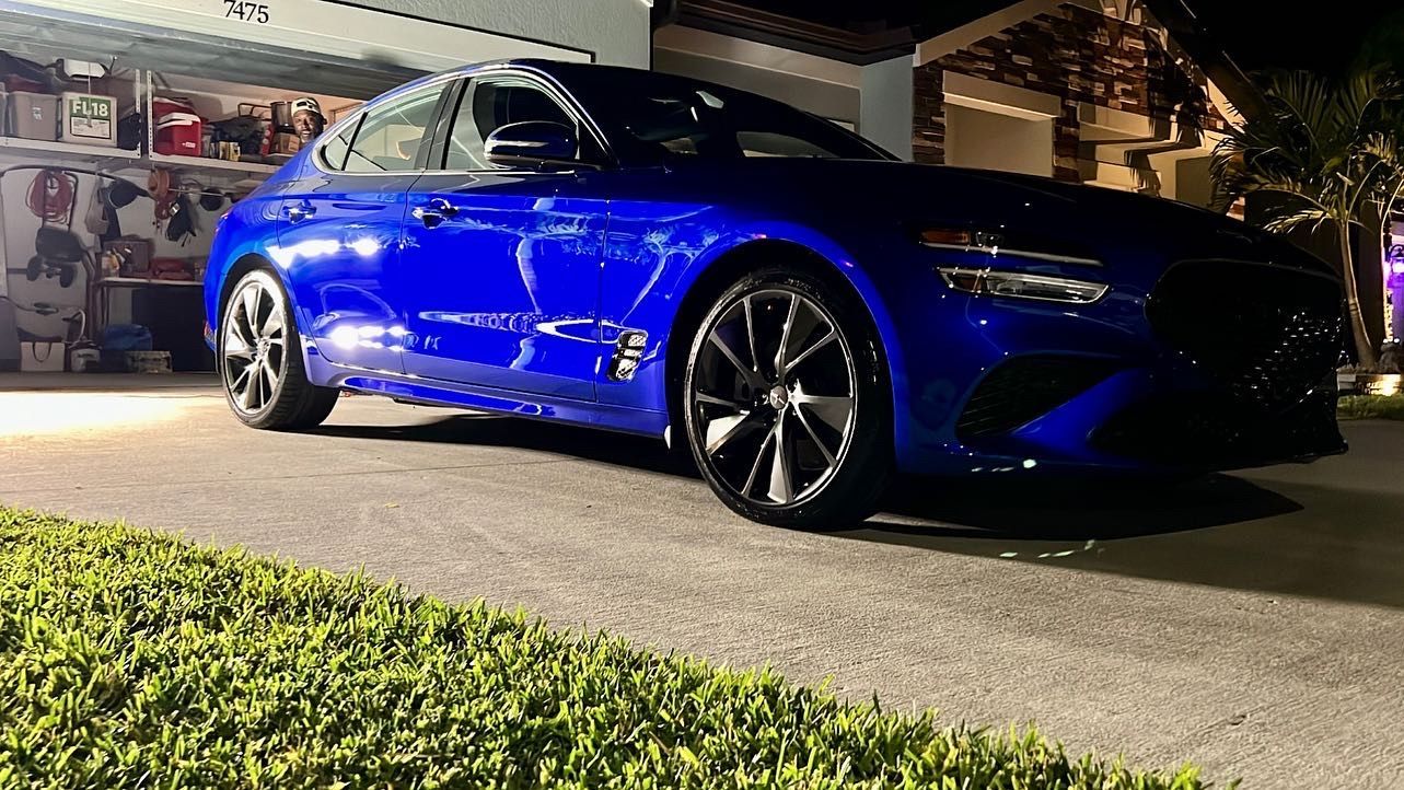 A blue car is parked in front of a garage at night.