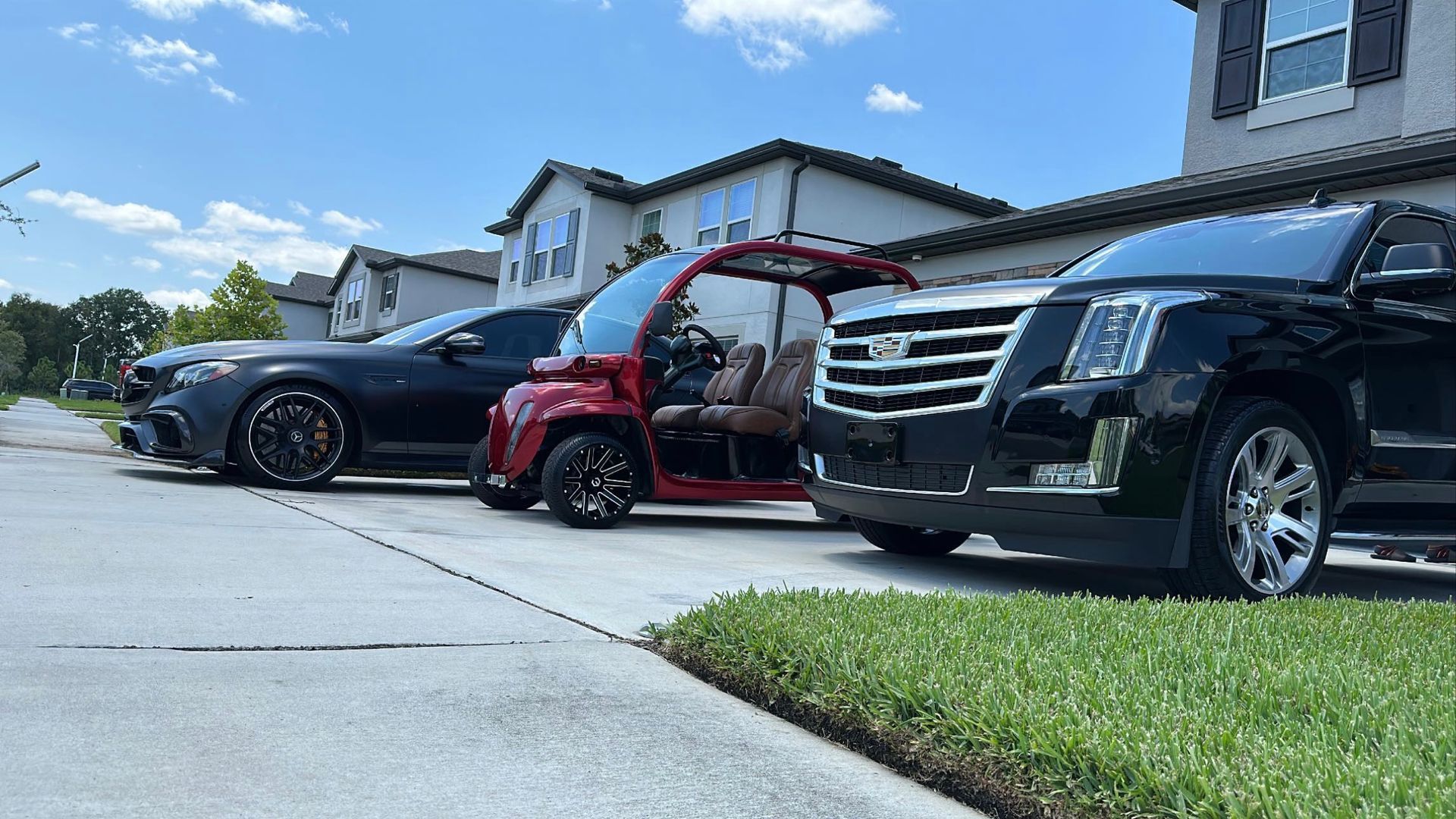 Three cars are parked on the side of the road in front of a house.