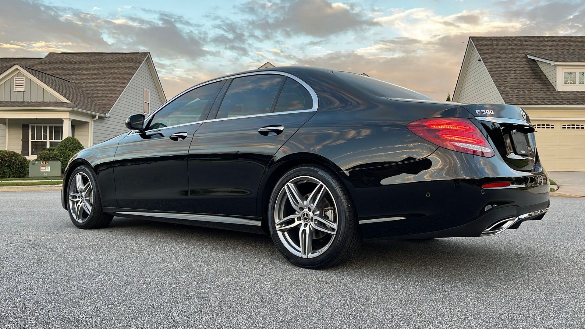 A black mercedes benz e class is parked in front of a house.