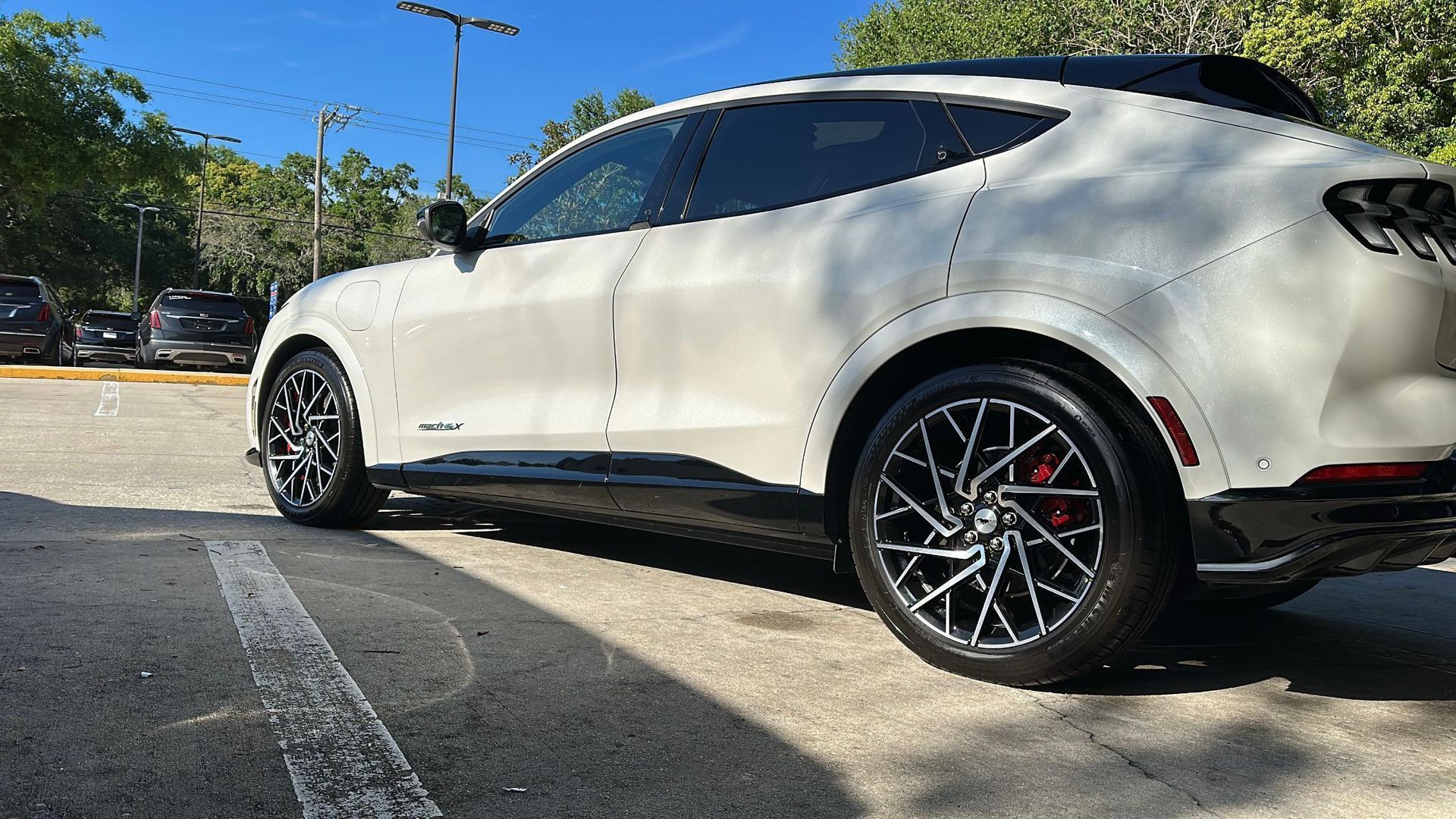 A white ford mustang mach e is parked in a parking lot.