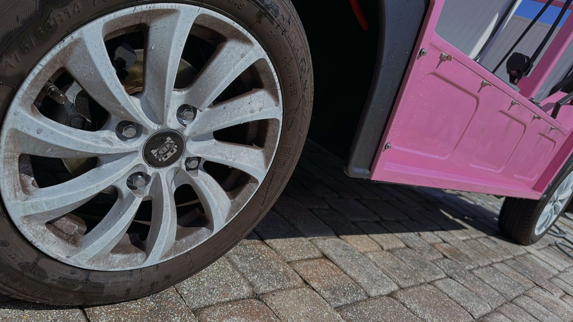 A close up of a car wheel on a brick road.