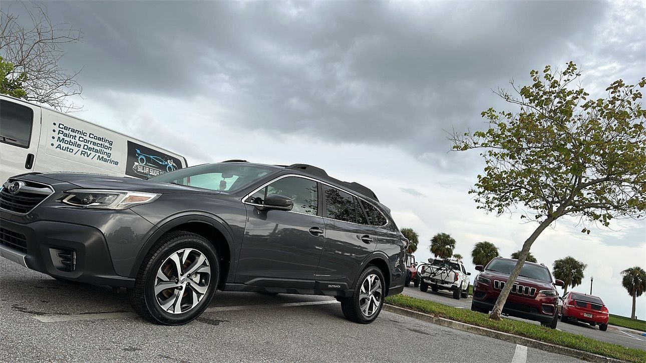 A gray suv is parked on the side of the road in a parking lot.