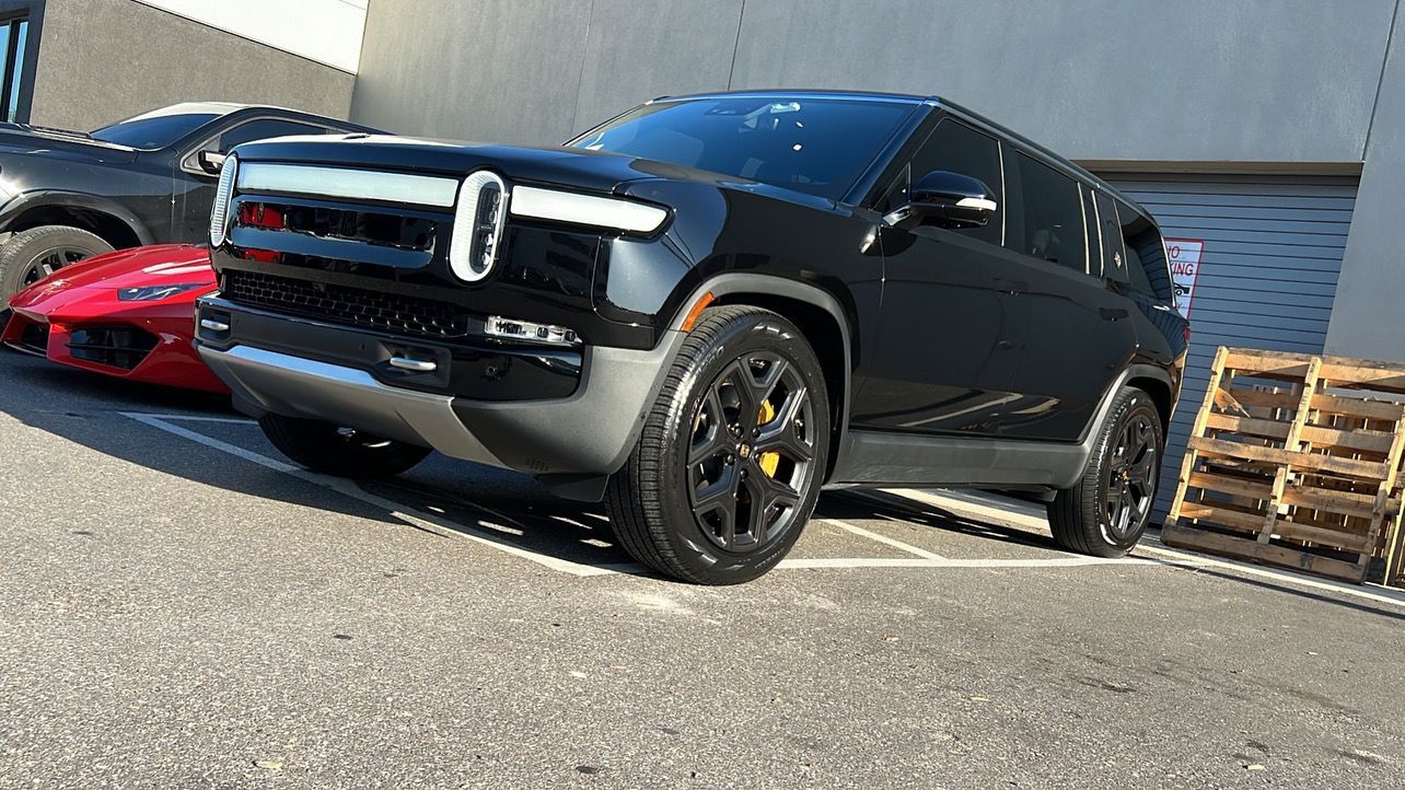 A black suv is parked next to a red sports car in a parking lot.
