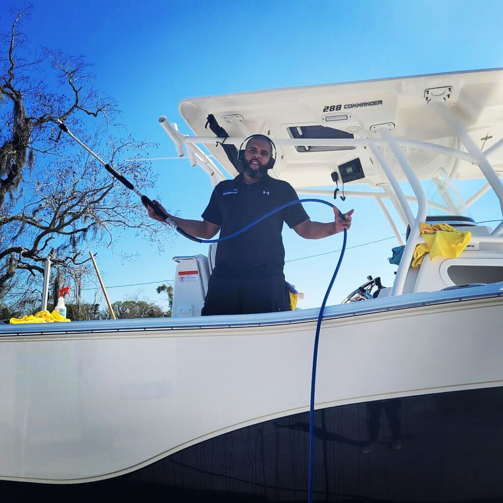 A man is standing on the deck of a boat holding a hose