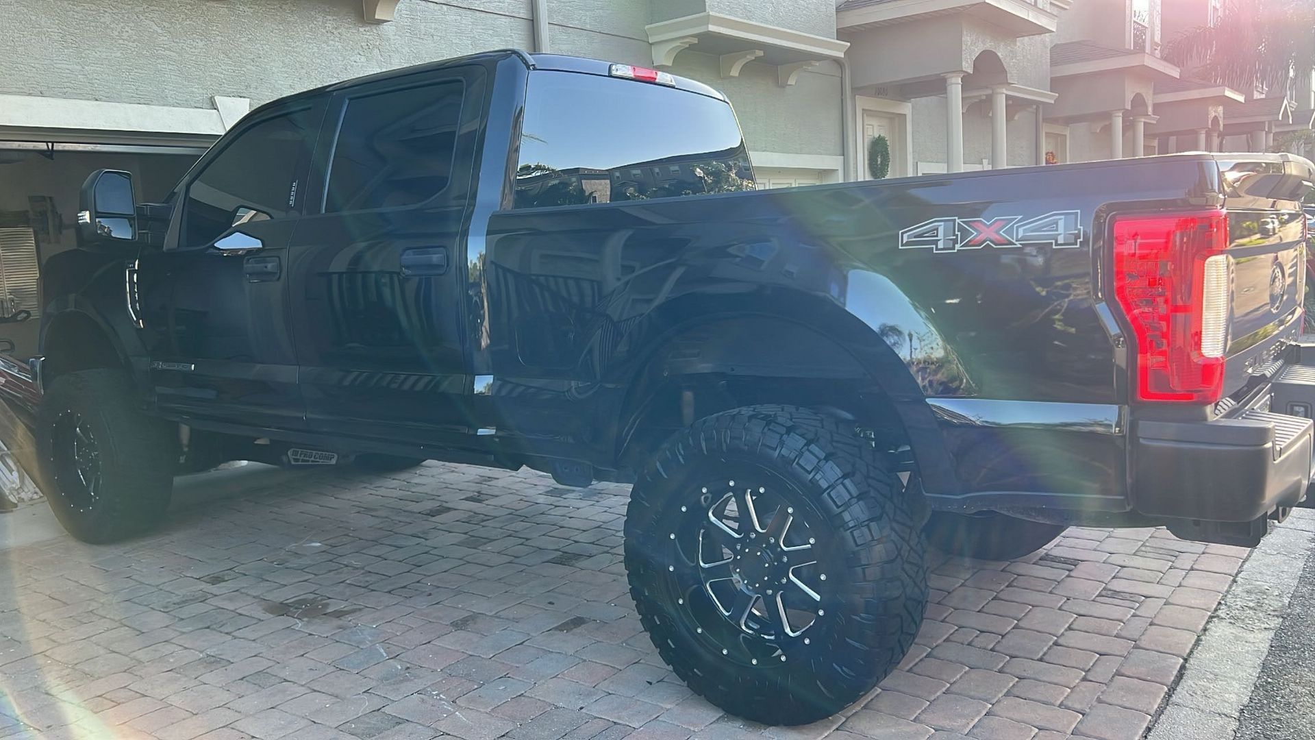 A black truck is parked on a brick driveway in front of a building.