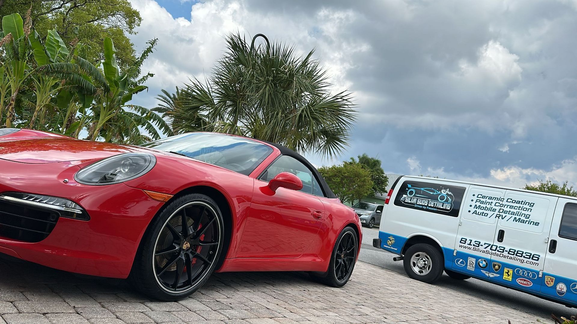 A red sports car is parked next to a white van.