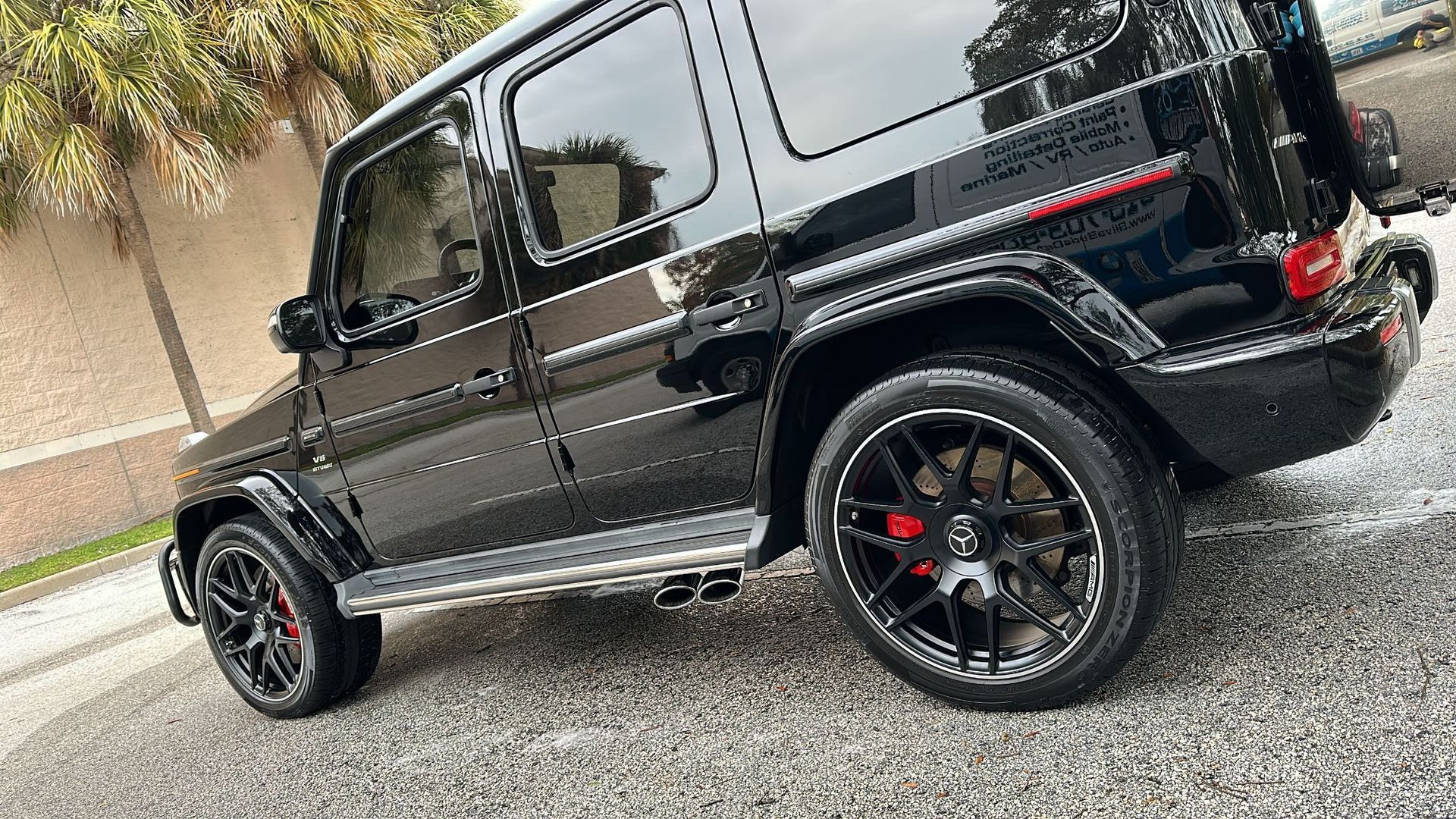 A black mercedes benz g63 is parked on the side of the road.
