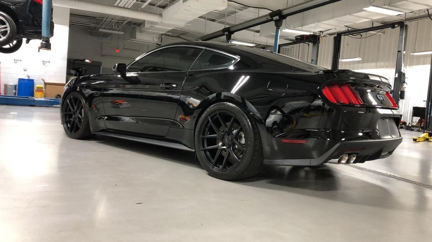 A black ford mustang is parked in a garage.