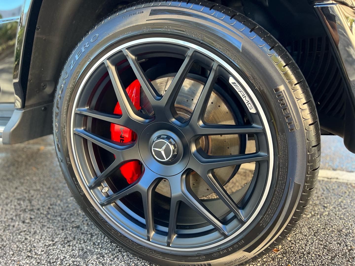 A close up of a mercedes wheel with red brake calipers