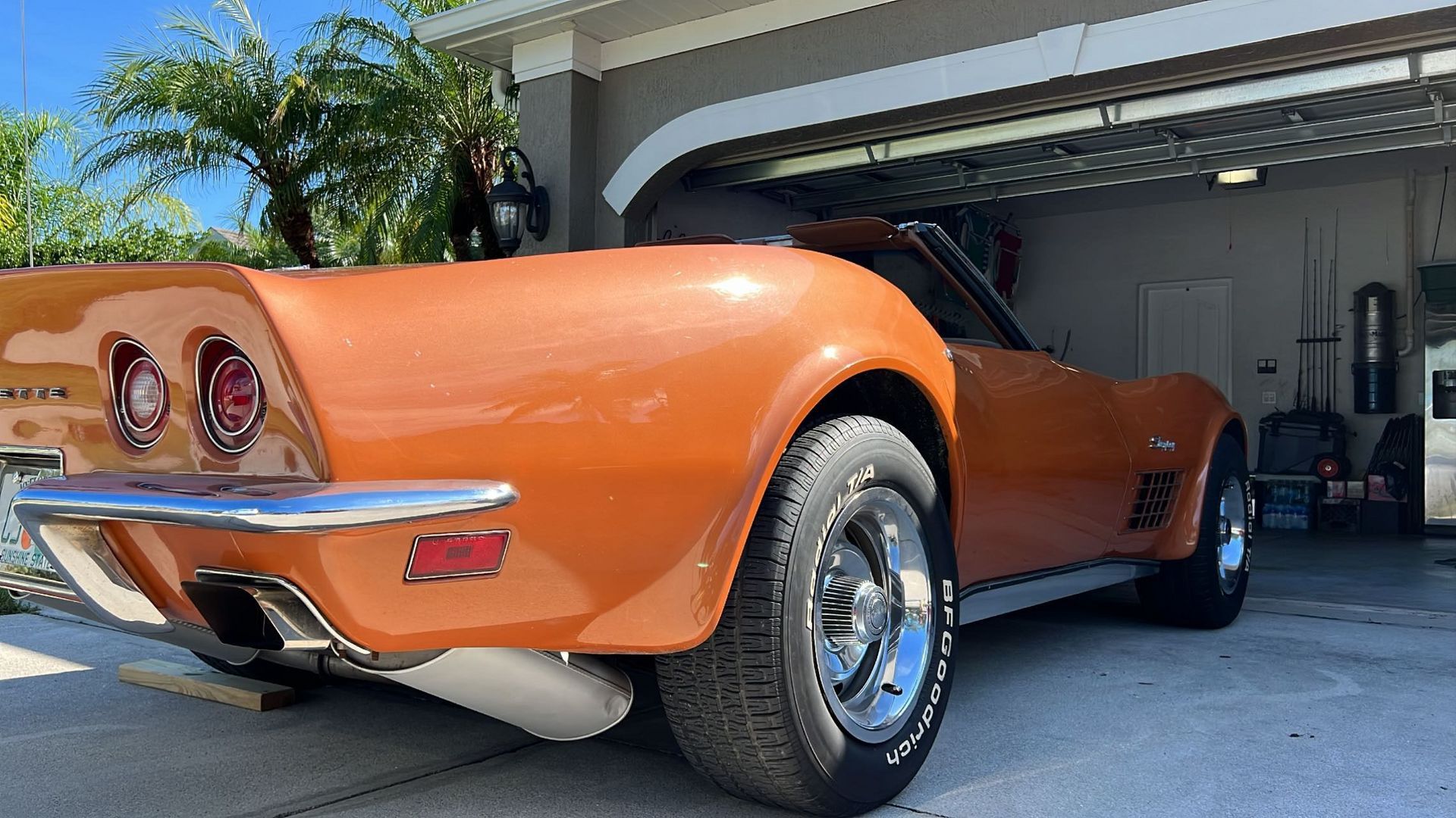 An orange corvette is parked in a garage.