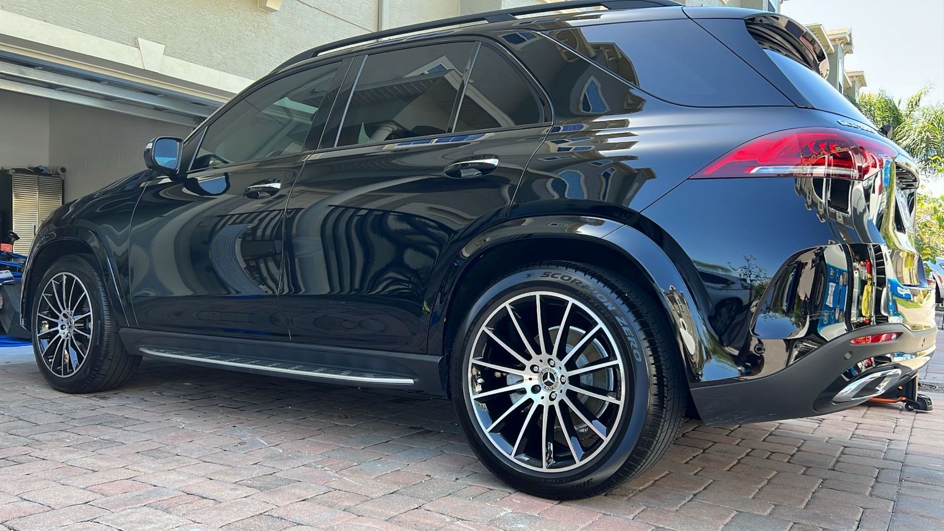 A black suv is parked on a brick driveway in front of a building.