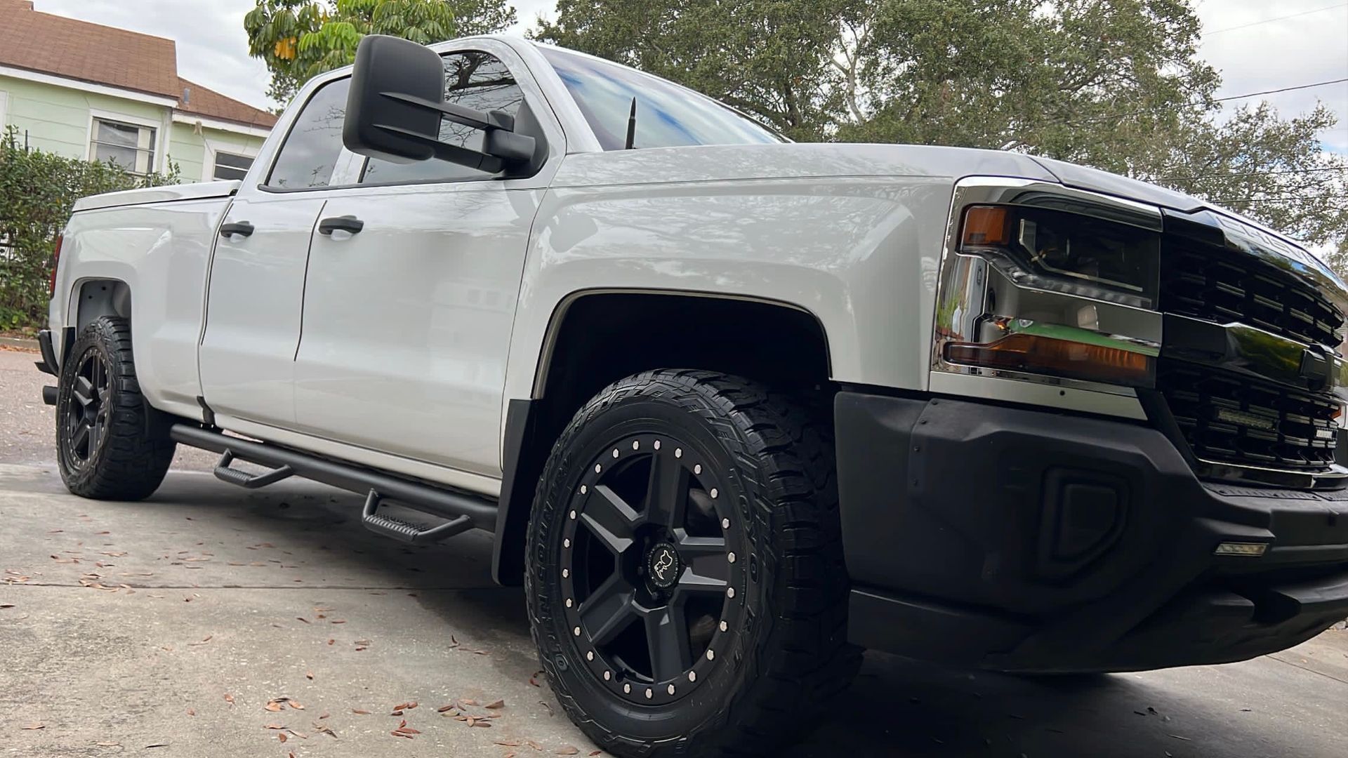 A white truck is parked in a driveway next to a house.