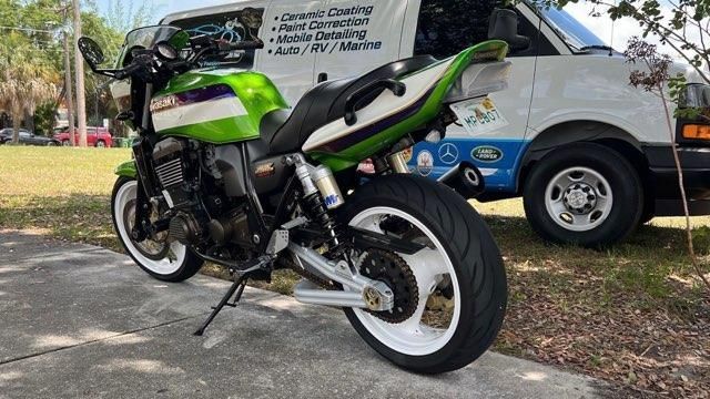 A green and white motorcycle is parked next to a white van.