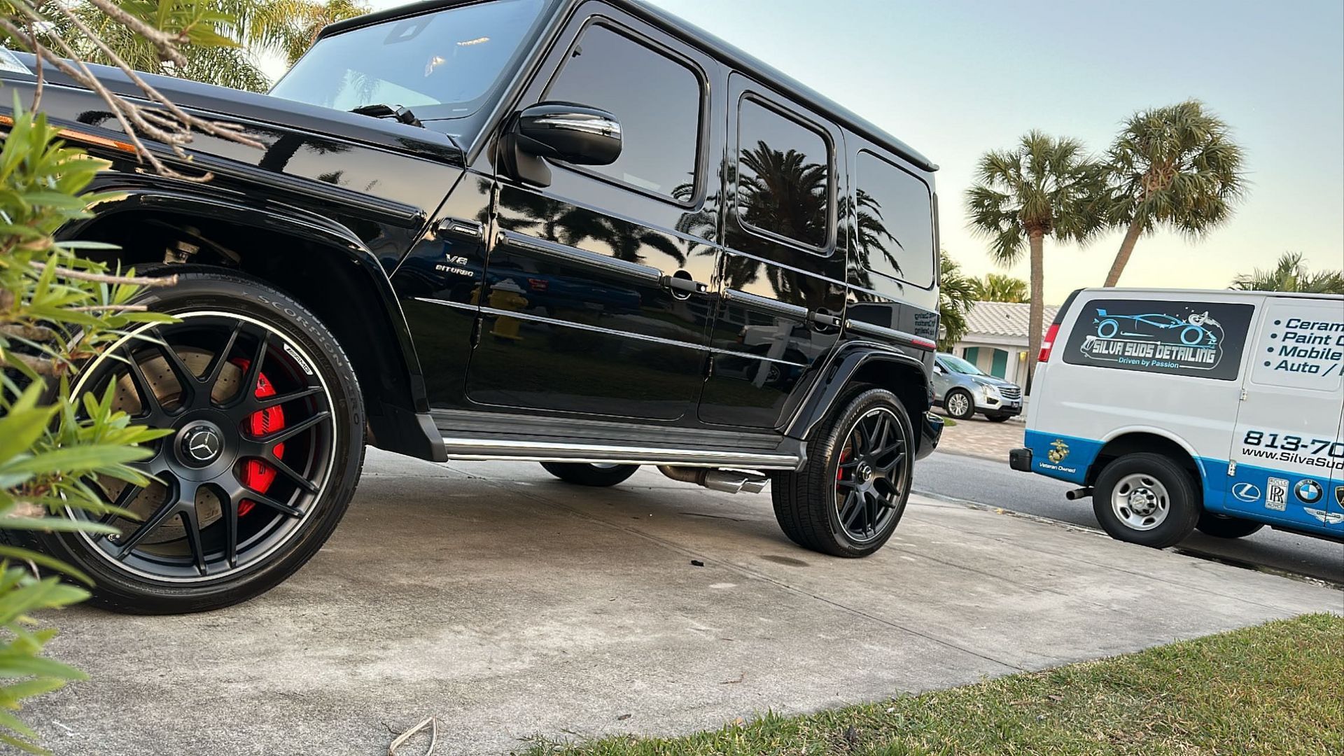 A black suv is parked in a driveway next to a white van.