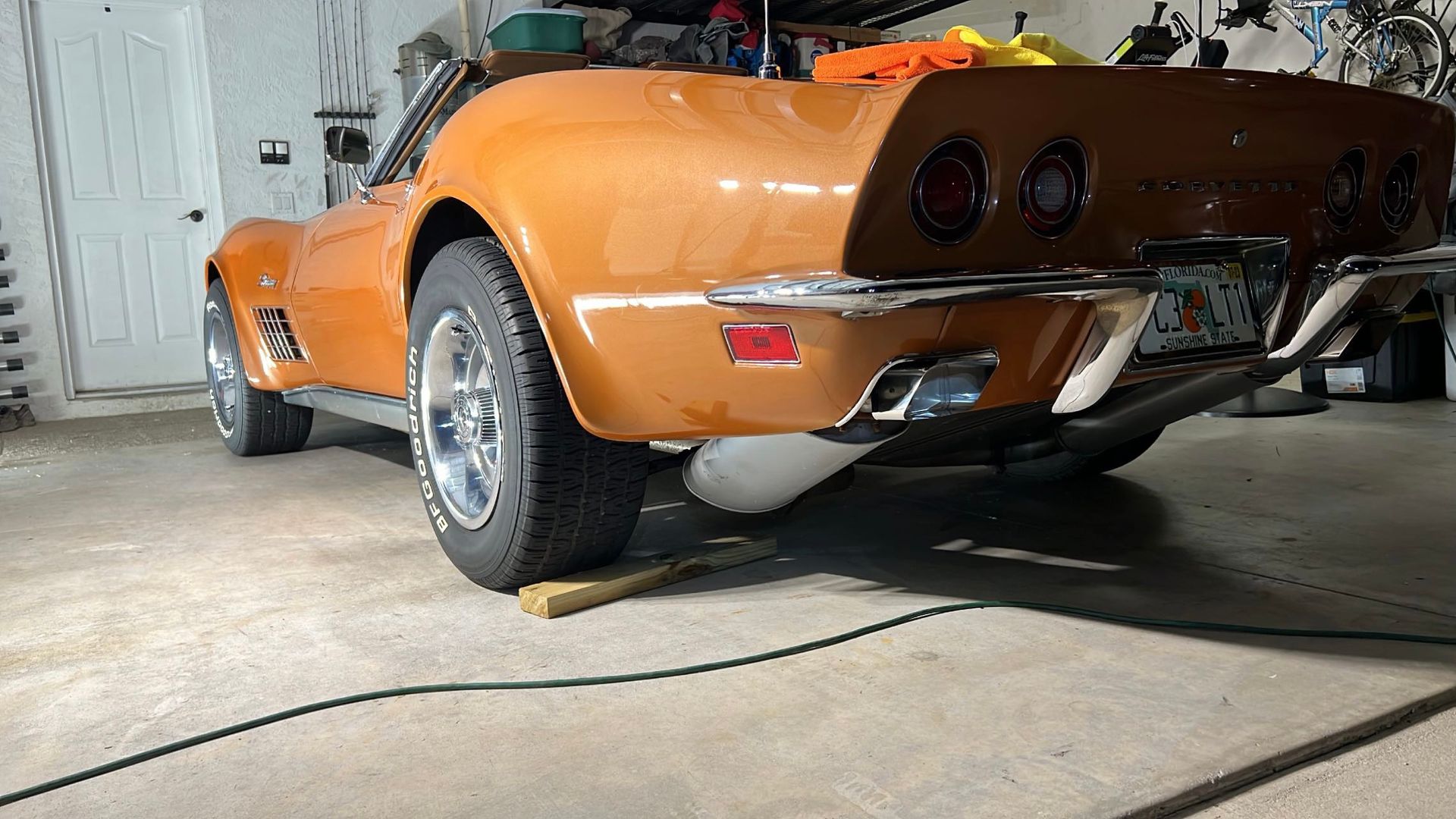An orange corvette convertible is parked in a garage.