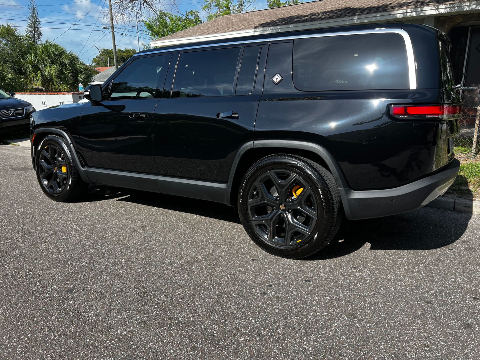 A black suv is parked on the side of the road in front of a house.