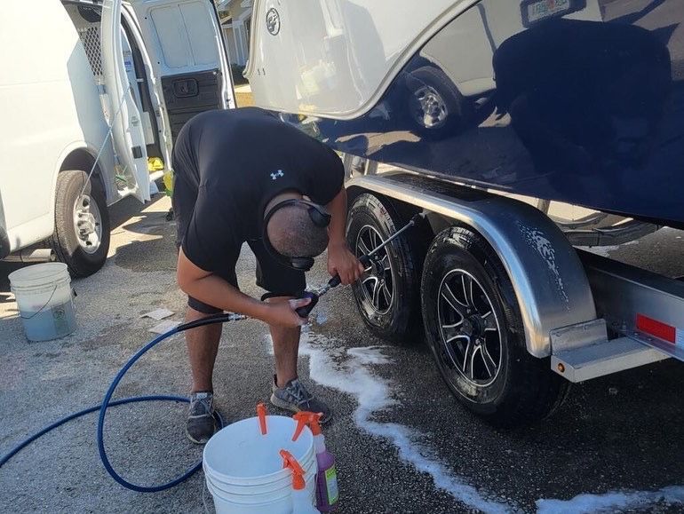 A man is cleaning the tires of a boat trailer