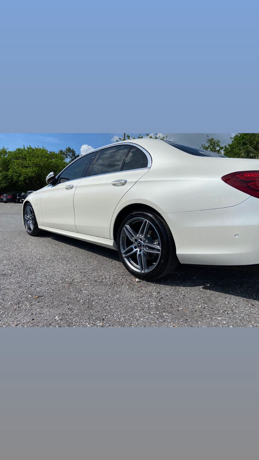 A white mercedes benz e class is parked in a parking lot.