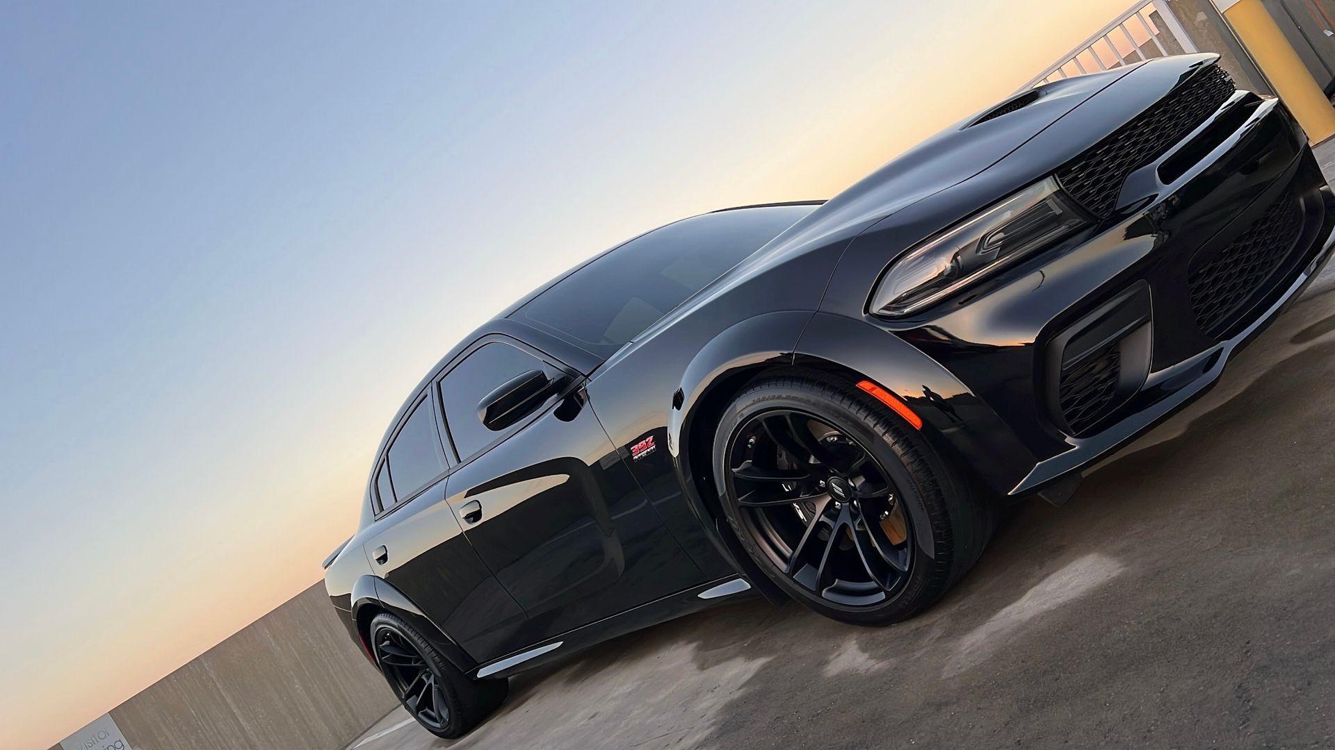 A black dodge charger is parked in a parking lot.