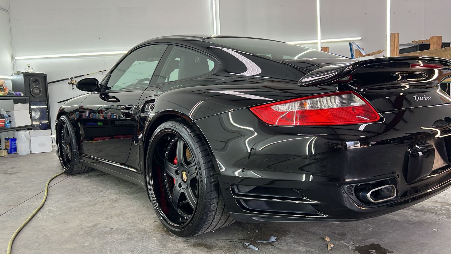 A black porsche turbo is sitting in a garage.