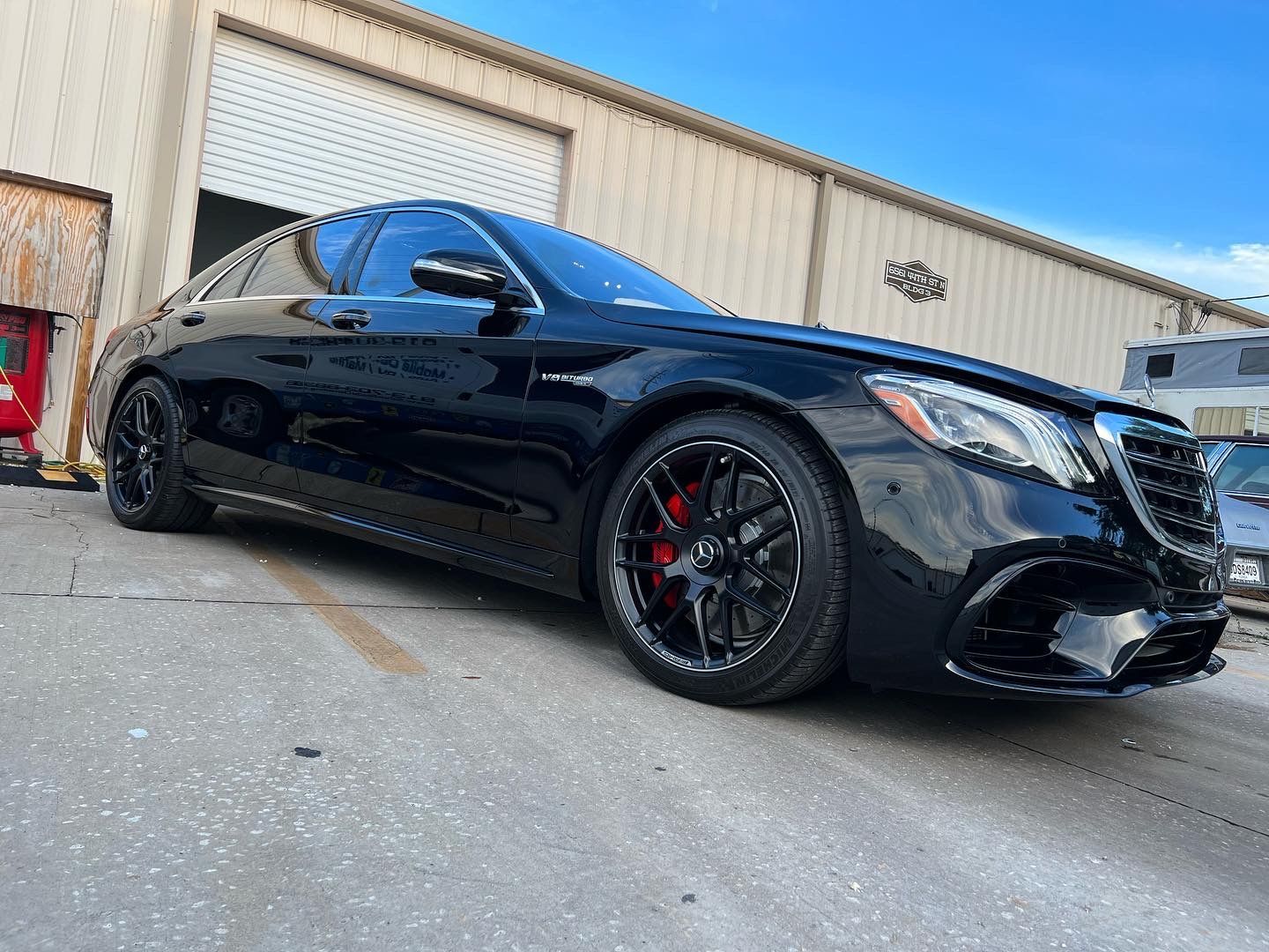 A black mercedes benz s63 amg is parked in front of a building.