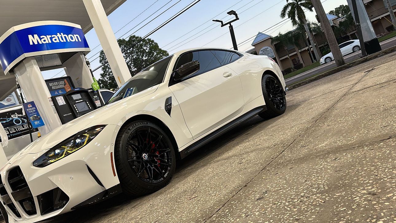 A white sports car is parked in front of a gas station.