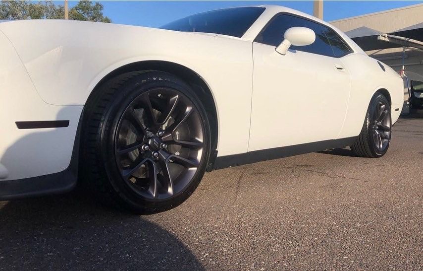 A white dodge challenger is parked in a parking lot.