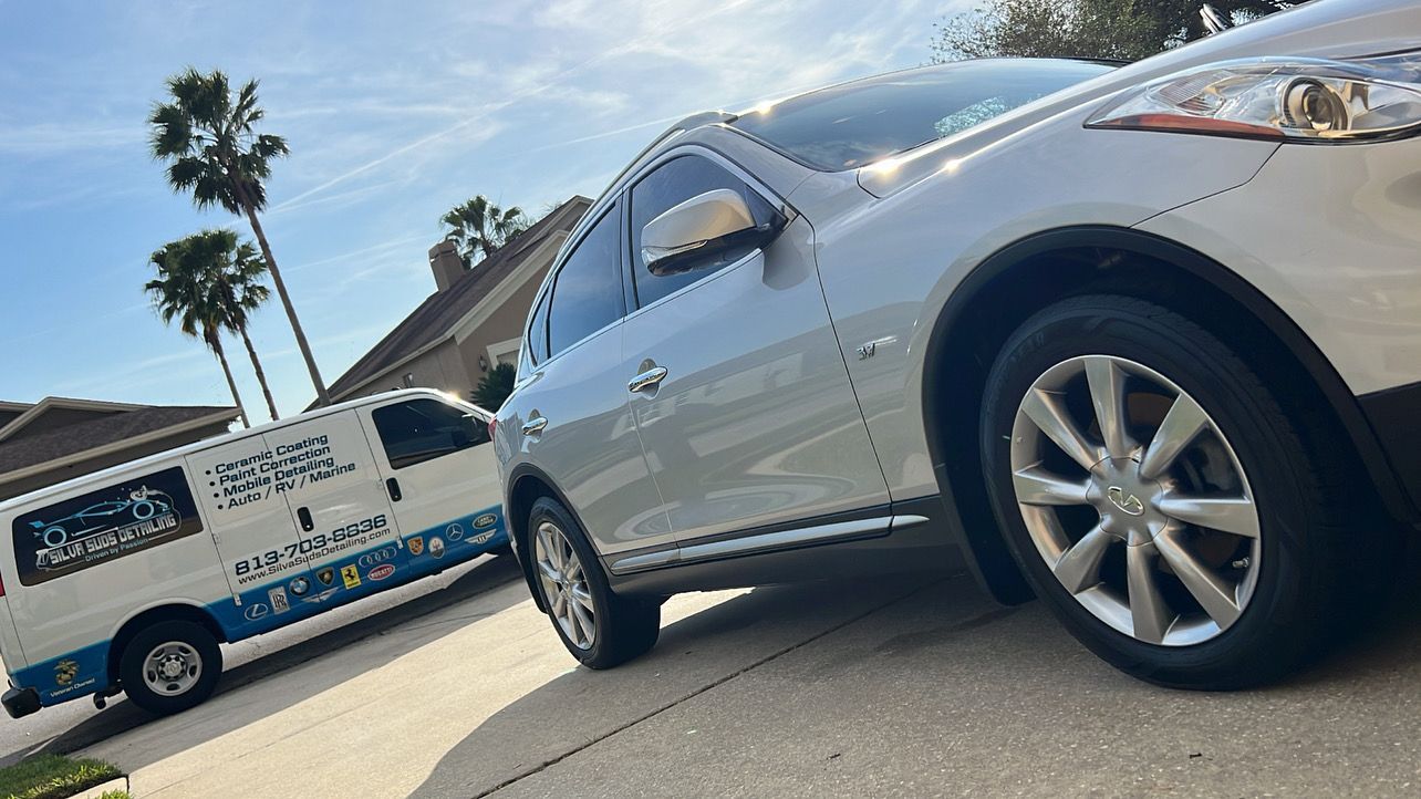 A silver car is parked next to a white van.