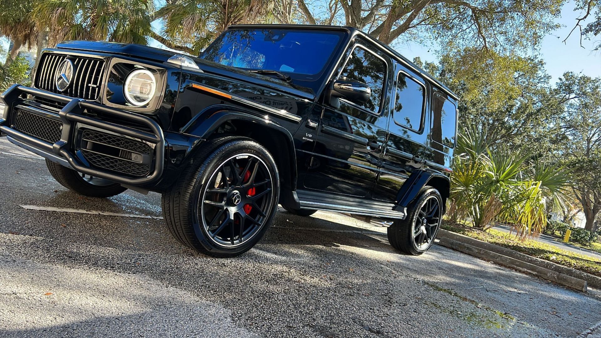 A black mercedes benz g63 amg is parked on the side of a road.