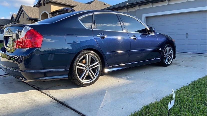 A blue car is parked in a driveway in front of a garage.