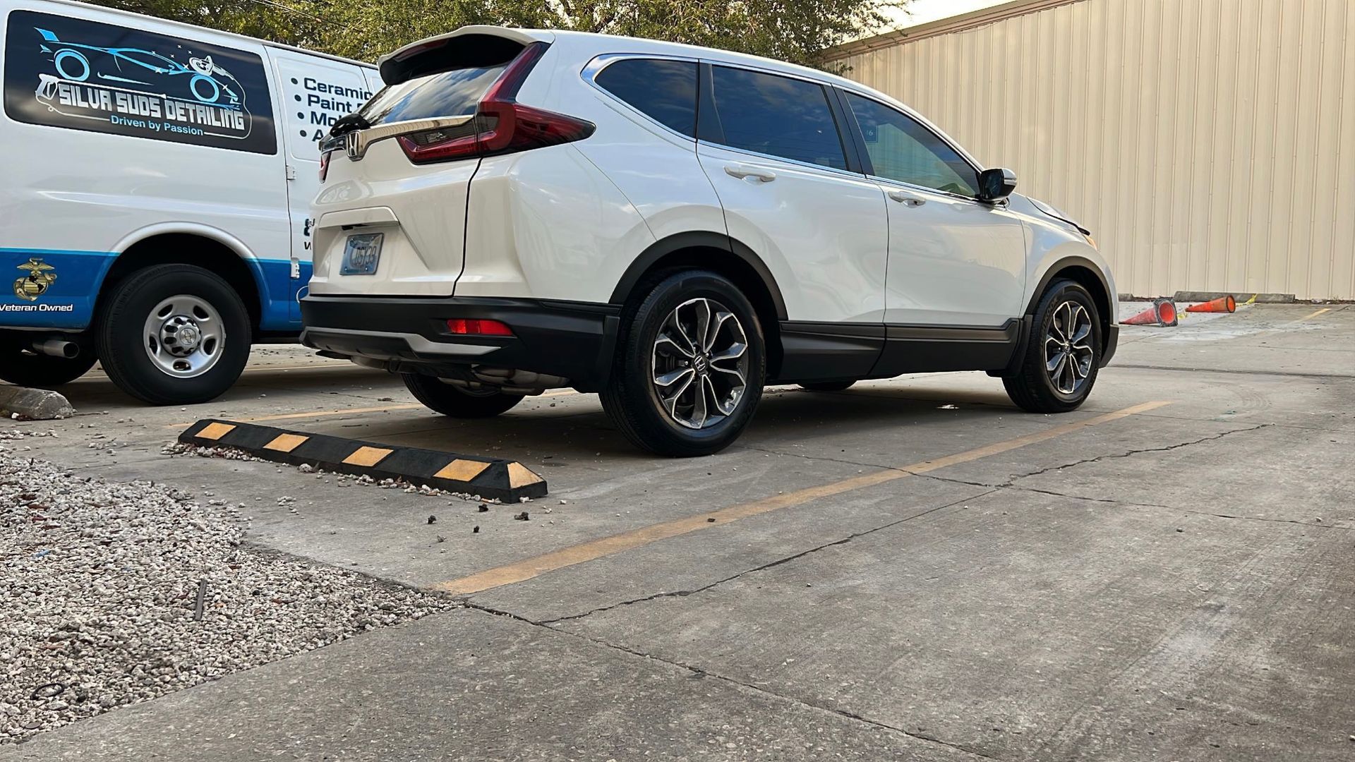 A white suv is parked in a parking lot next to a white van.