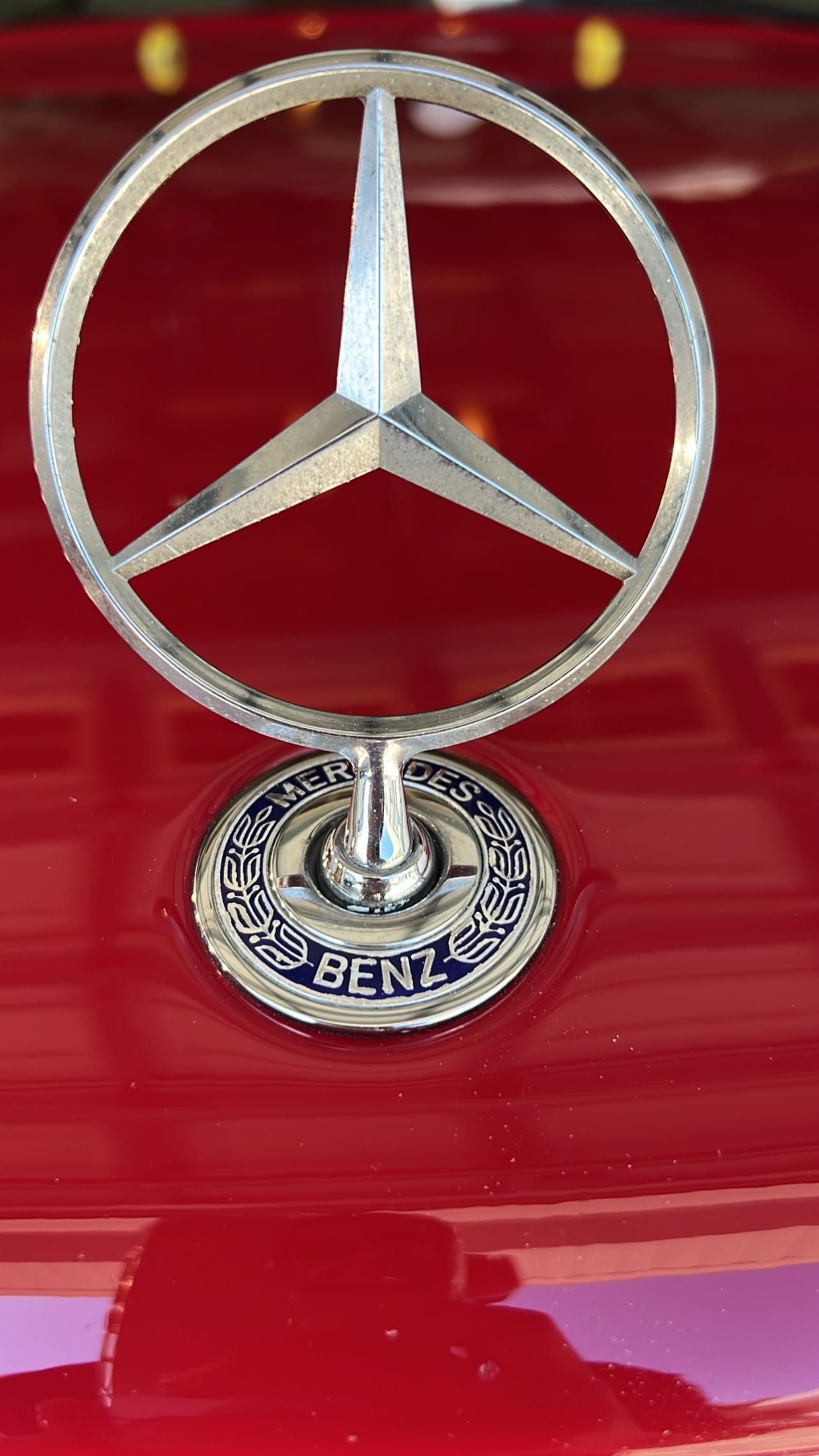 A close up of a mercedes benz emblem on a red car