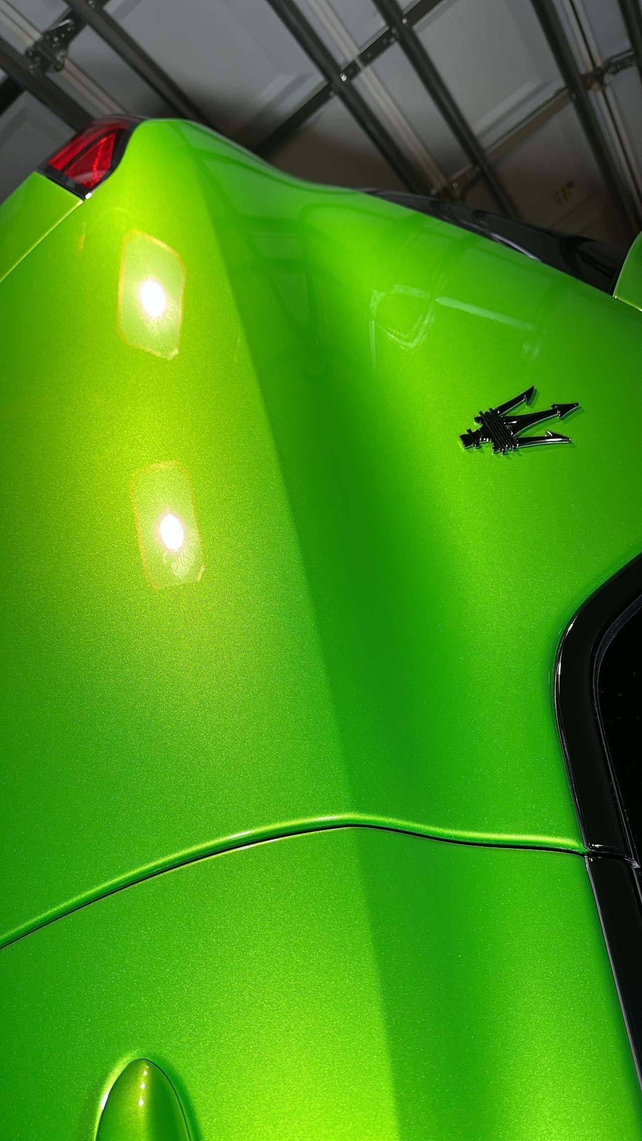 A close up of a green car in a garage.