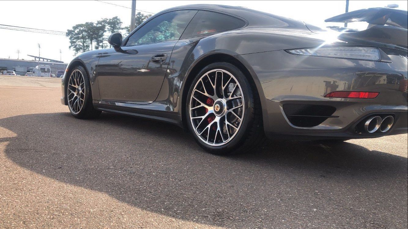 A gray porsche 911 turbo is parked on the side of the road.
