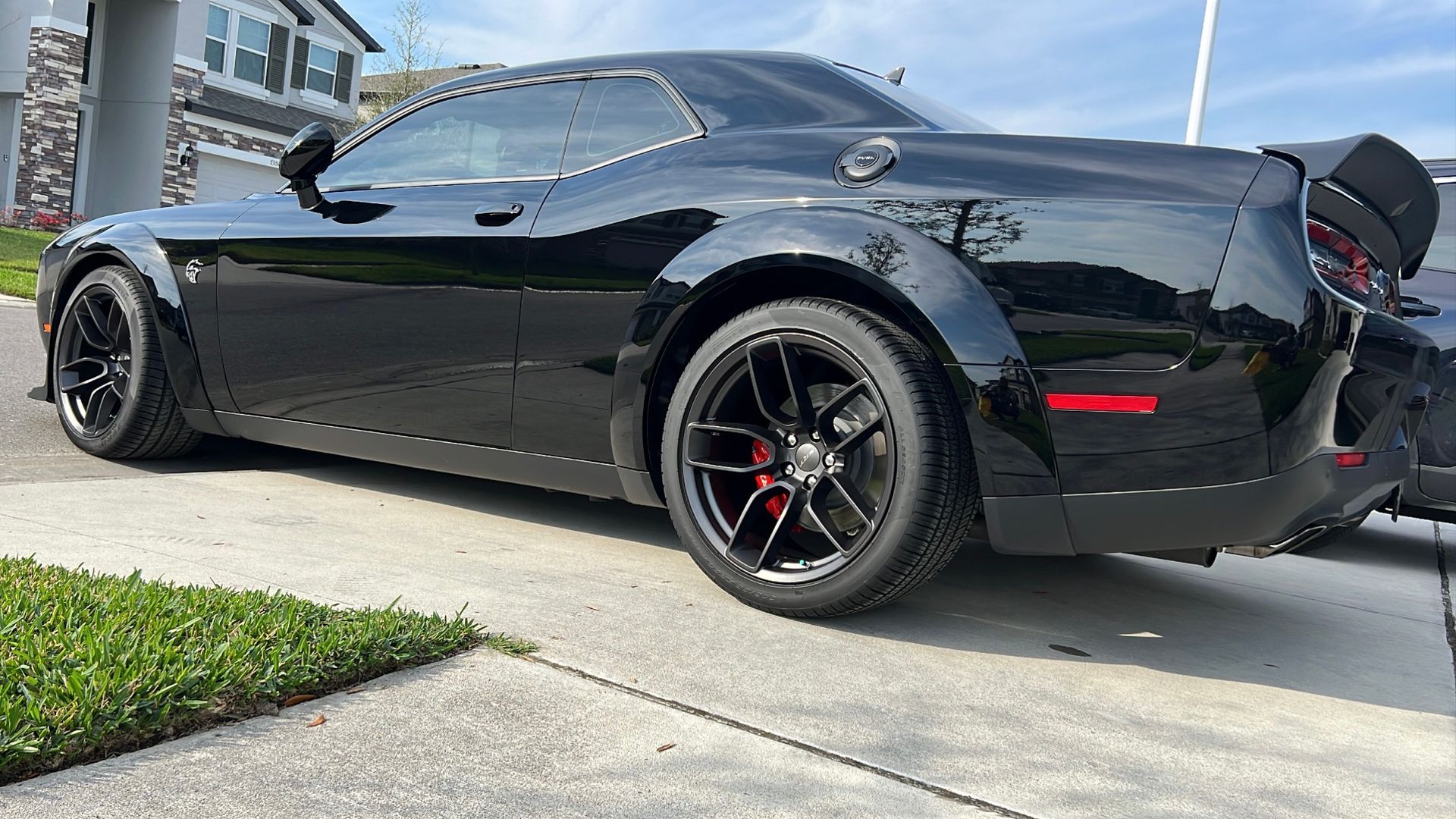 A black dodge challenger is parked on the side of the road.