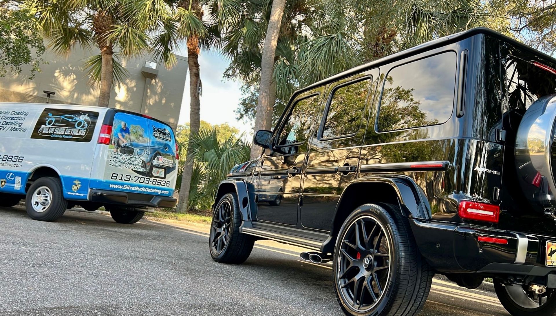A black jeep is parked next to a white van.