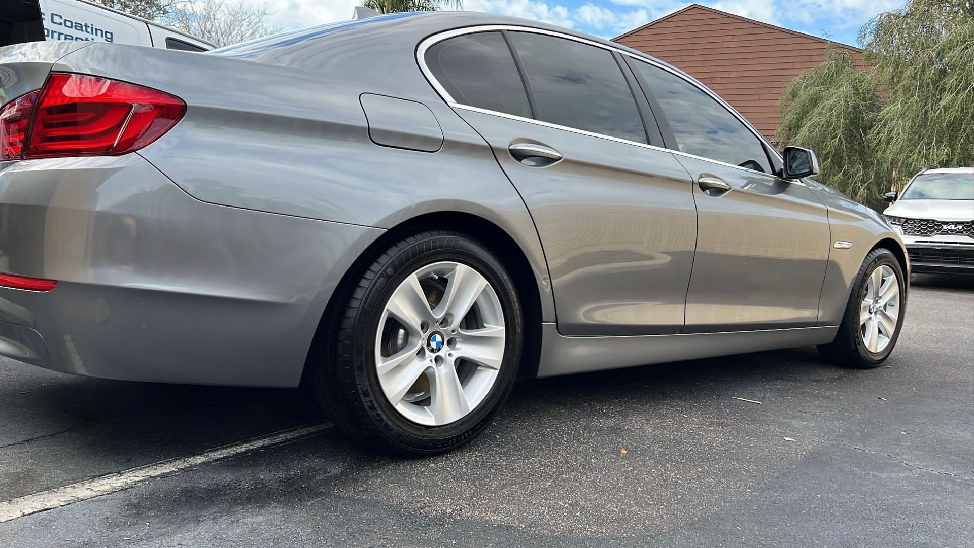 A silver bmw 5 series is parked in a parking lot.