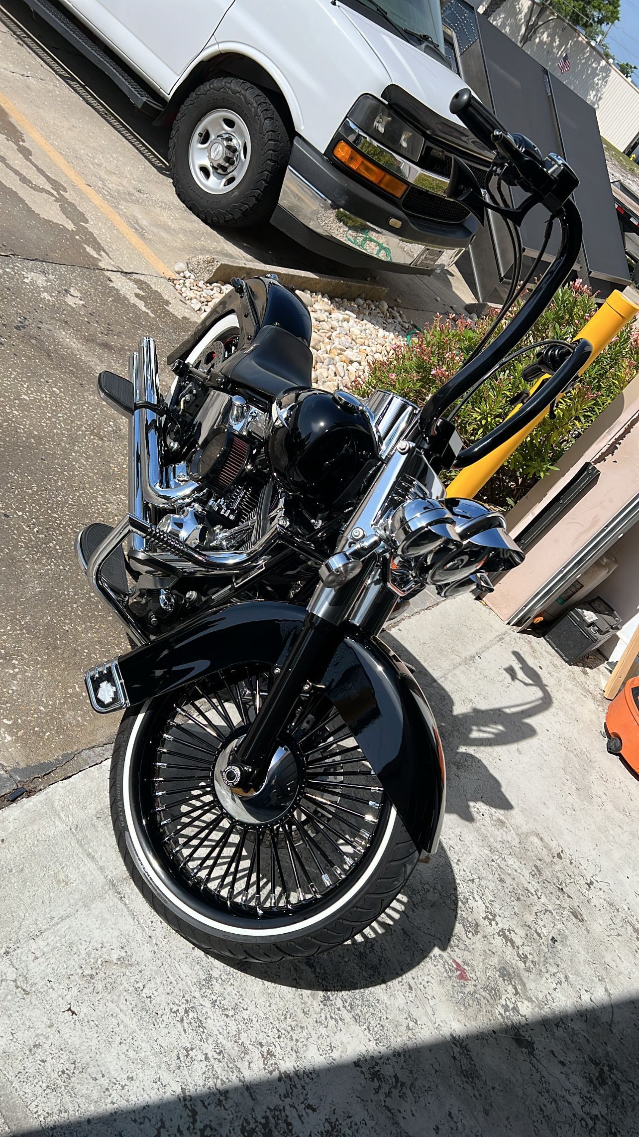 A motorcycle is parked on the side of the road next to a white van.