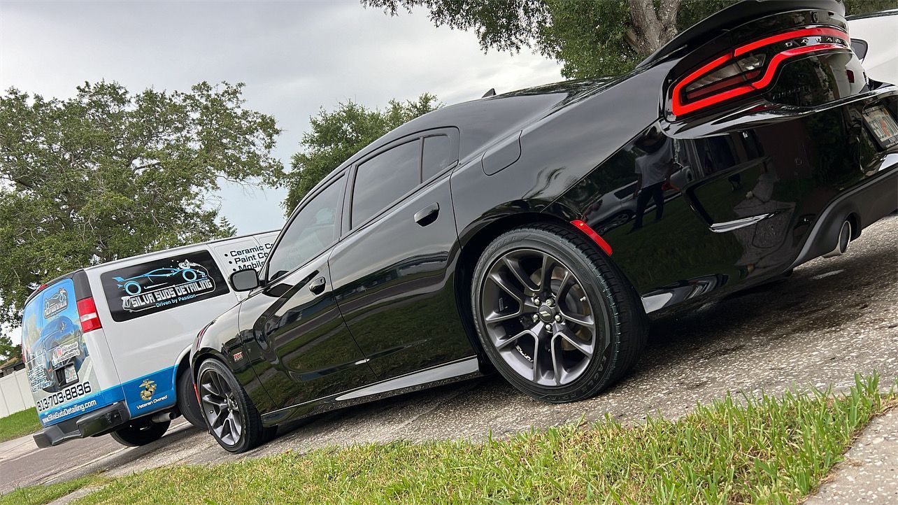 A black car is parked next to a white van on the side of the road.