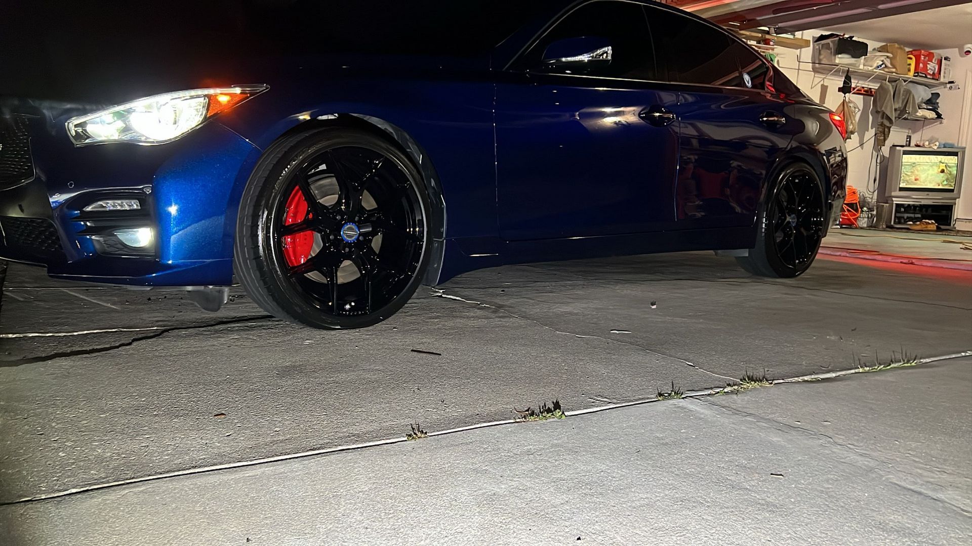 A blue car is parked in a garage at night.