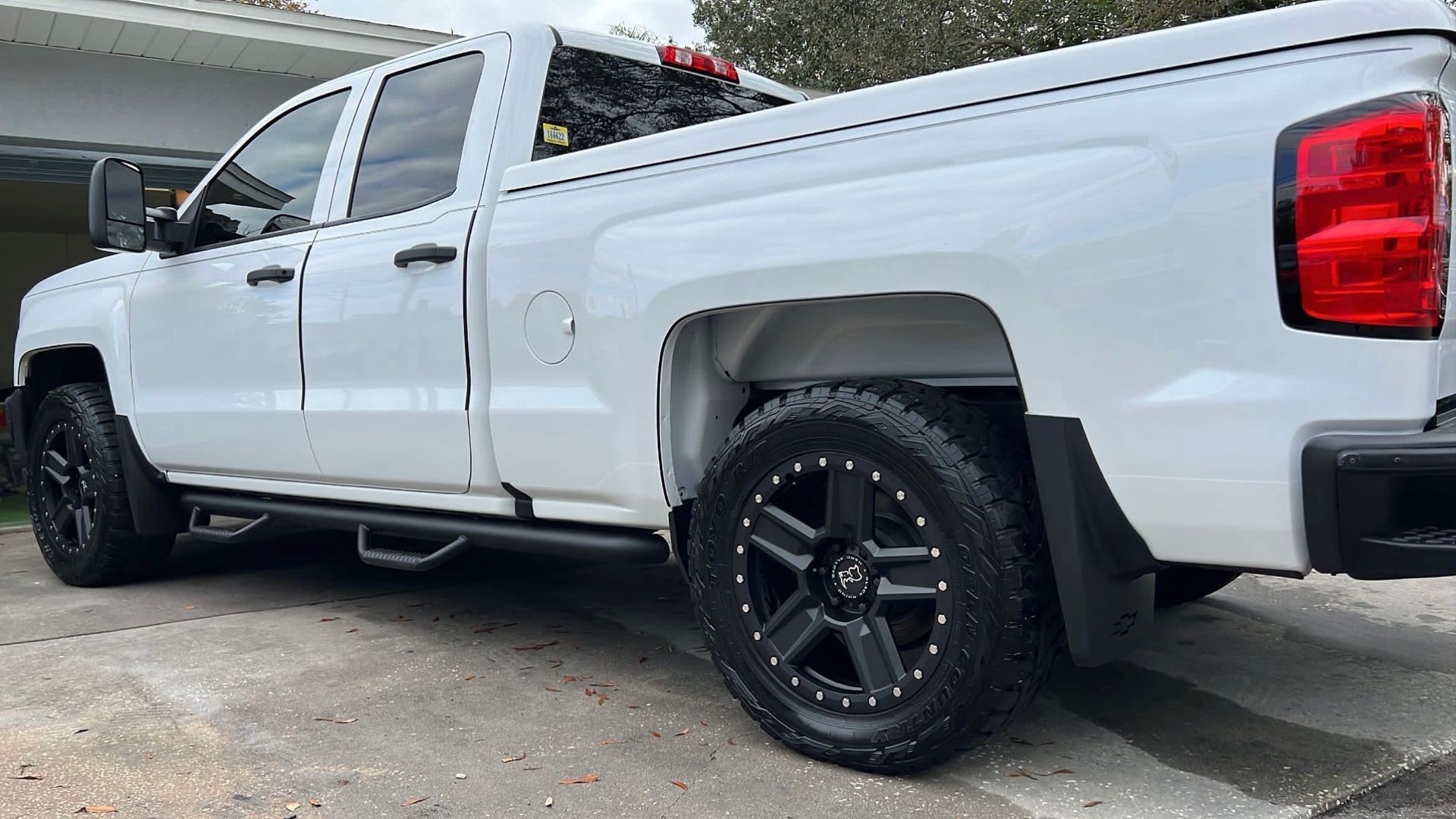 A white truck is parked in front of a garage.
