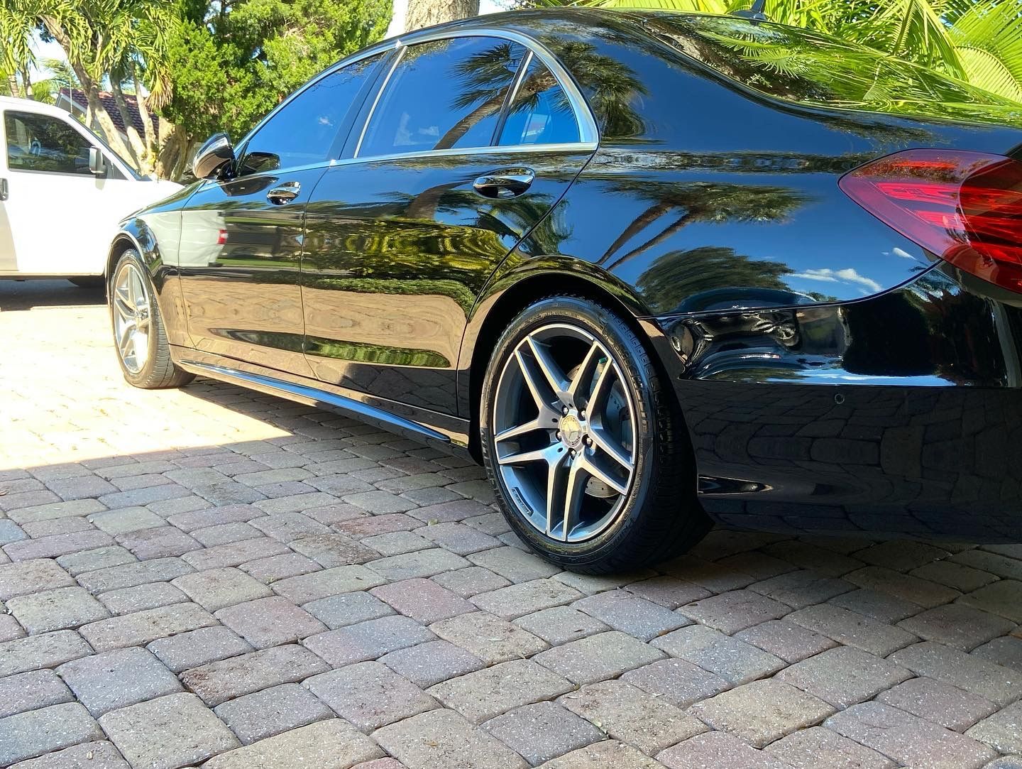 A black car is parked on a brick driveway.