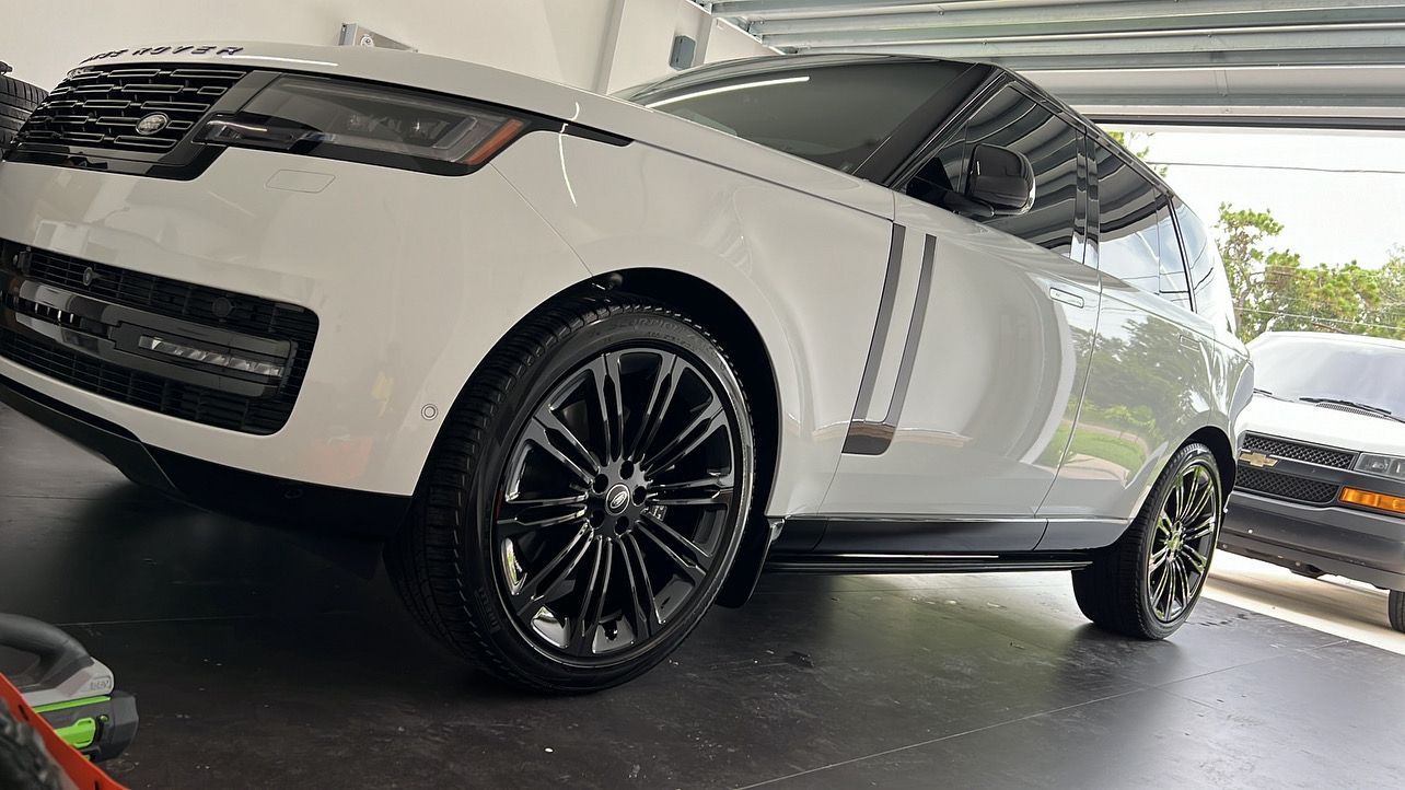 A white car is parked in a garage with black wheels.