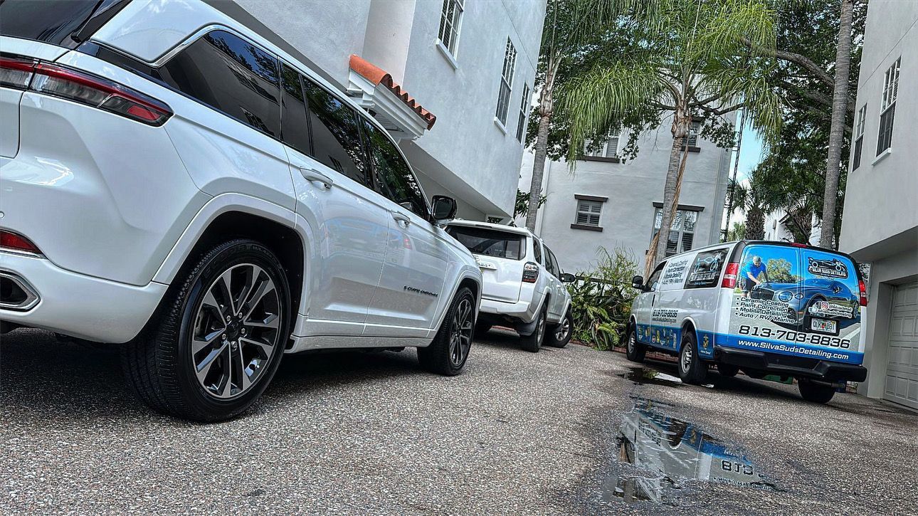 A white jeep is parked in a driveway next to a building.