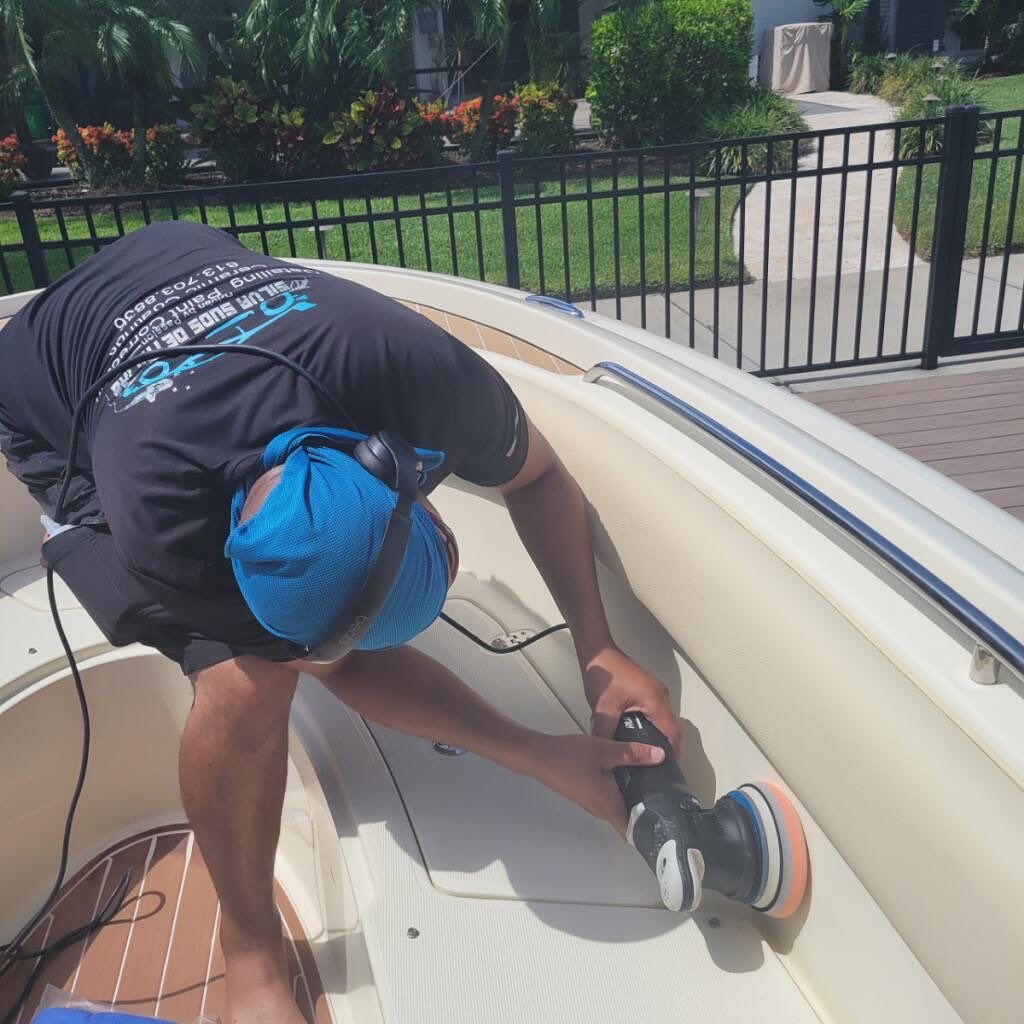 A man wearing a blue hat is polishing a boat