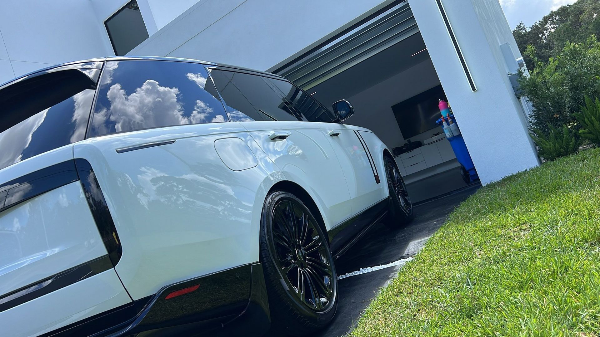 A white range rover is parked in front of a garage.